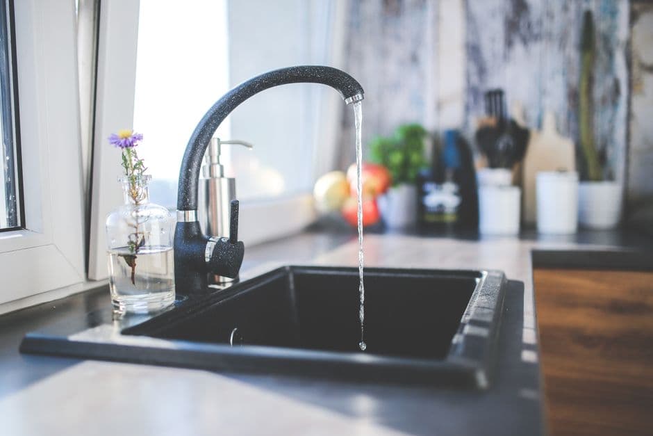 Water running from a modern kitchen faucet into a sink