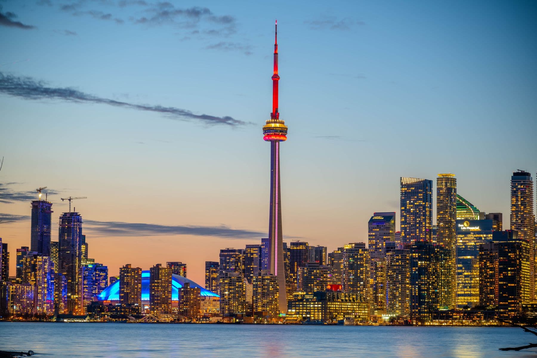 The Toronto skyline and CN Tower lit up at dusk over the lake — the city Drainman INC serves